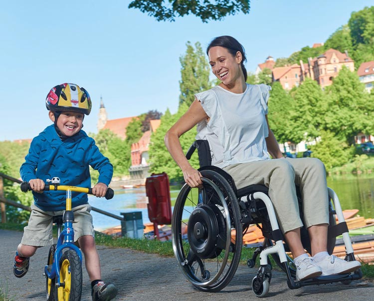 Mamma i rullstol med barn som cyklar bredvid
